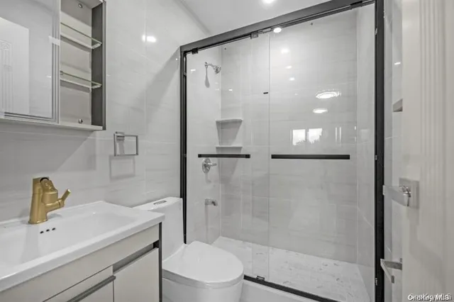 a bathroom with a shower sink vanity mirror and toilet