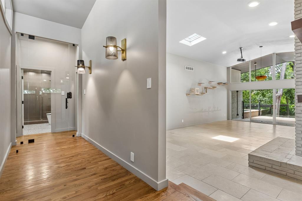 13321 Purple Sage Road Dallas, TX 75240 - Photo 16 of 30 Open concept interior featuring wood-finish flooring, a contemporary wall sconce, and a glass-enclosed shower entrance