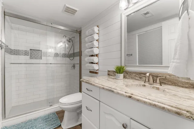 a bathroom with a granite countertop sink a toilet and shower