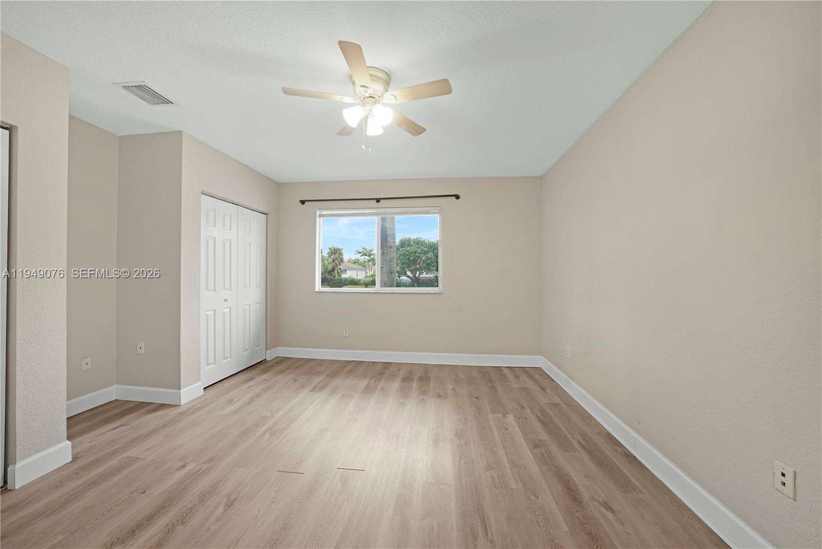 3533 Sonoma Drive Riviera Beach, FL 33404 - Photo 18 of 34 an empty room with wooden floor chandelier fan and windows