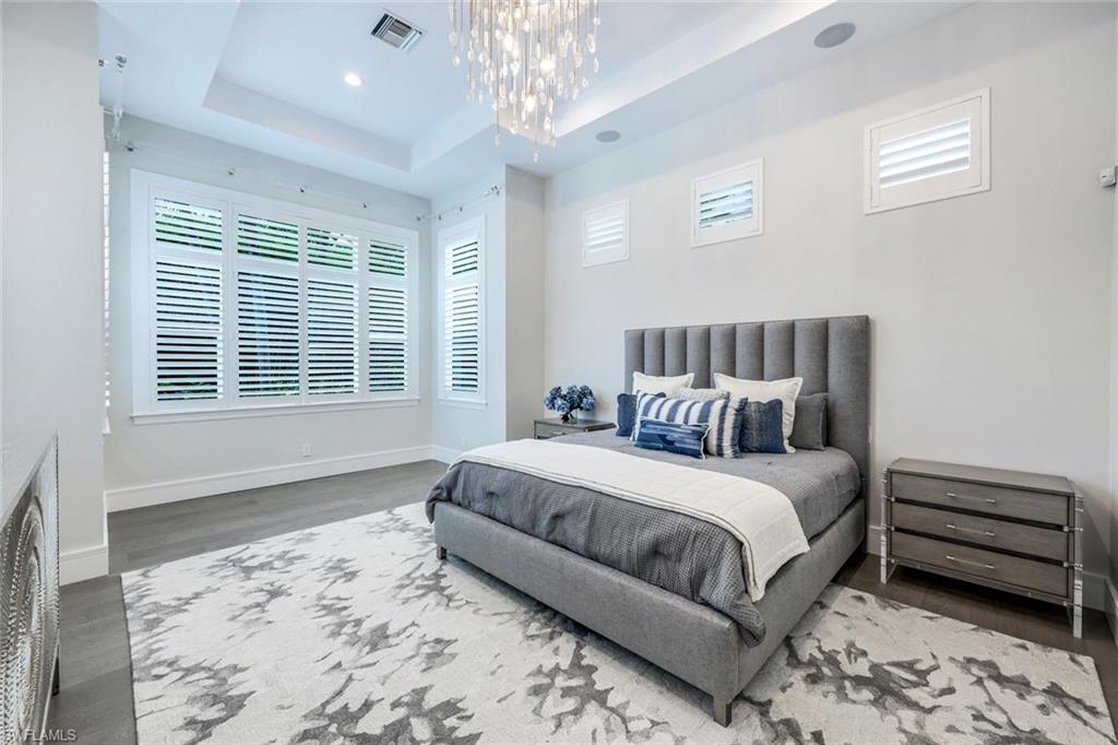 569 Neapolitan Way Naples, FL 34103 - Photo 14 of 50 a spacious bedroom with a bed a couch and large window