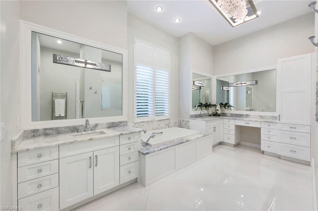 569 Neapolitan Way Naples, FL 34103 - Photo 16 of 50 a bathroom with a granite countertop double vanity sink a mirror and a bathtub