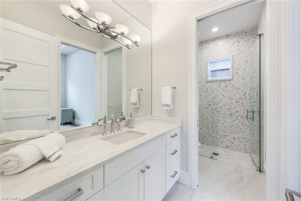569 Neapolitan Way Naples, FL 34103 - Photo 19 of 50 a bathroom with a double vanity sink mirror and shower