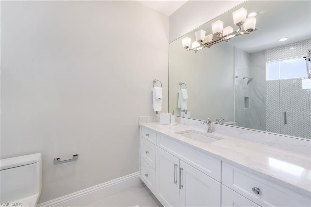 569 Neapolitan Way Naples, FL 34103 - Photo 21 of 50 a bathroom with a sink and a mirror