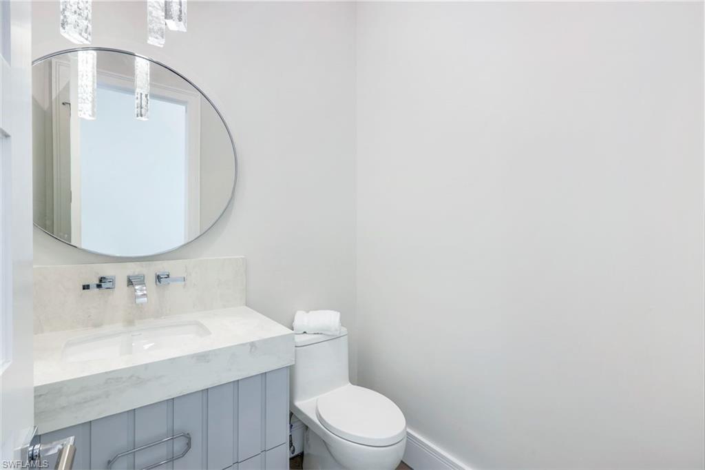 569 Neapolitan Way Naples, FL 34103 - Photo 26 of 50 a bathroom with a toilet a sink and mirror