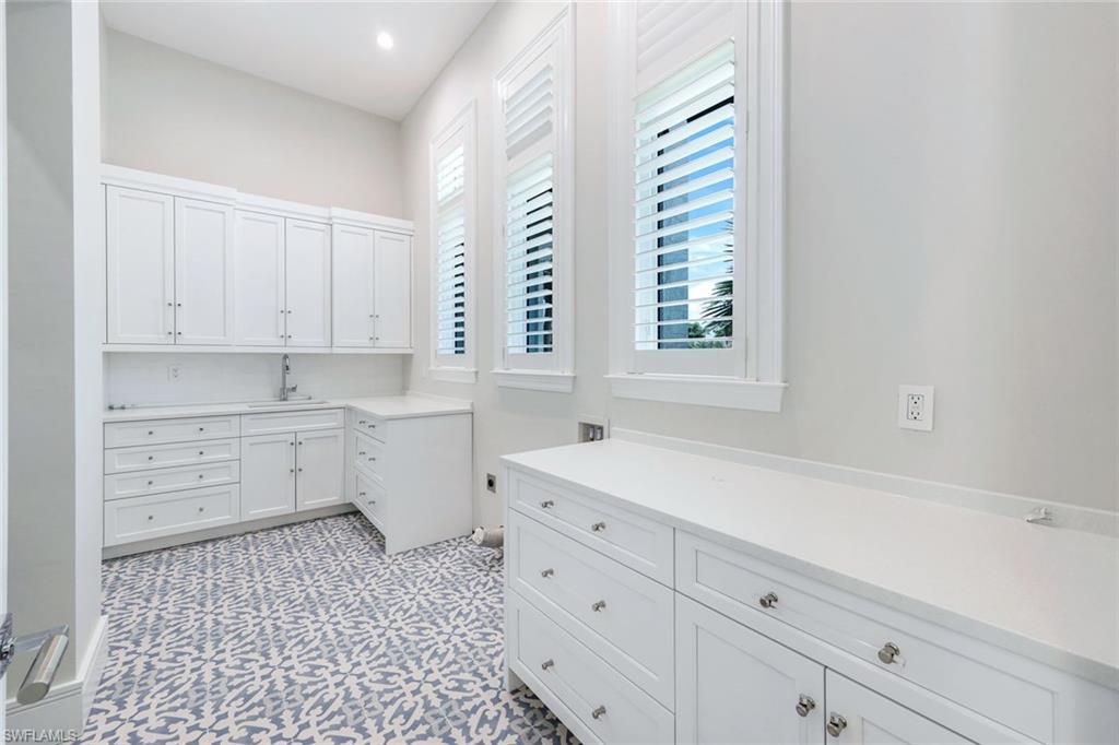 569 Neapolitan Way Naples, FL 34103 - Photo 27 of 50 a kitchen with white cabinets and white appliances