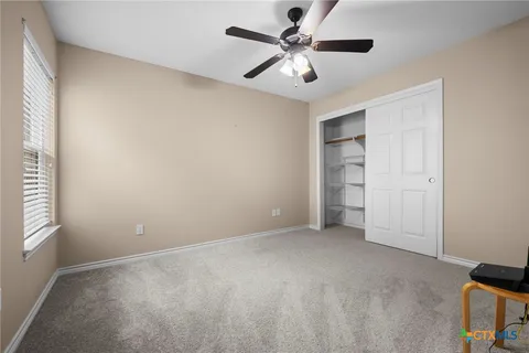 an empty room with windows and fan