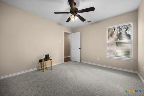 an empty room with windows and fan