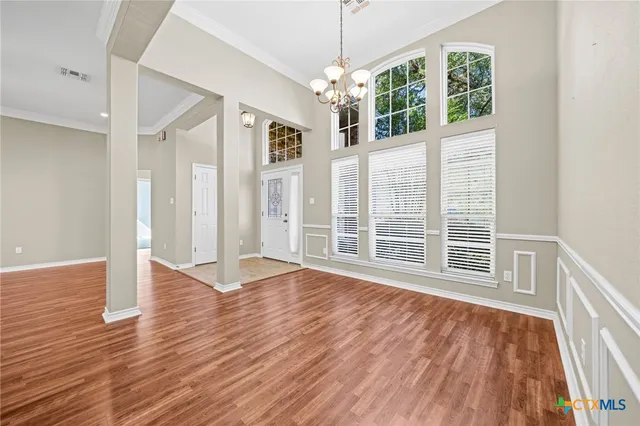 a view of an empty room with wooden floor chandeliers