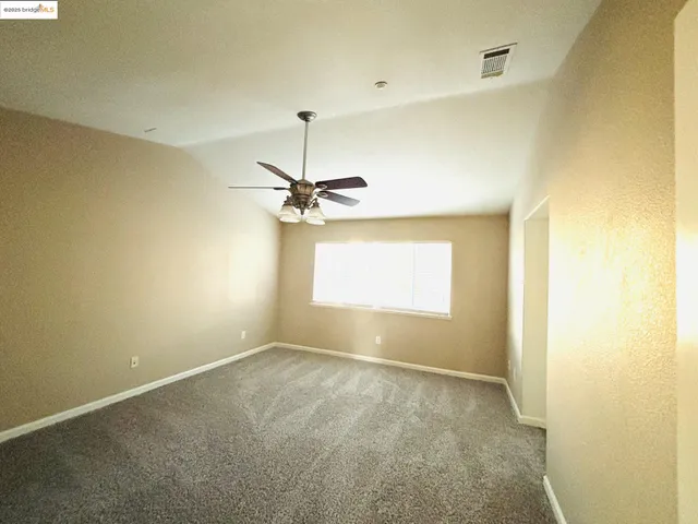 an empty room with a window and a ceiling fan