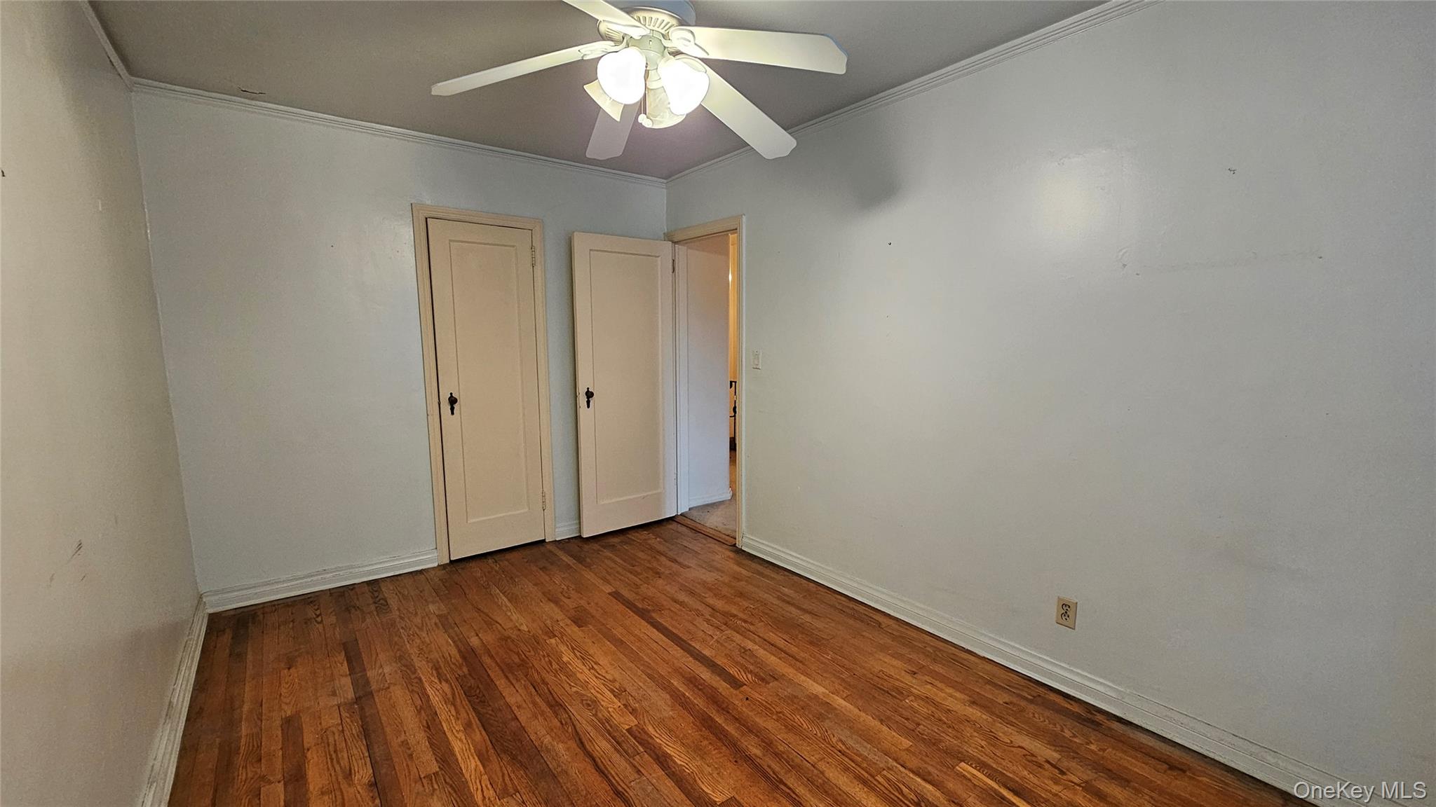 108-11 65th Road Queens, NY 11375 - Photo 13 of 22 Unfurnished bedroom featuring wood finished floors, ornamental molding, ceiling fan, and a closet