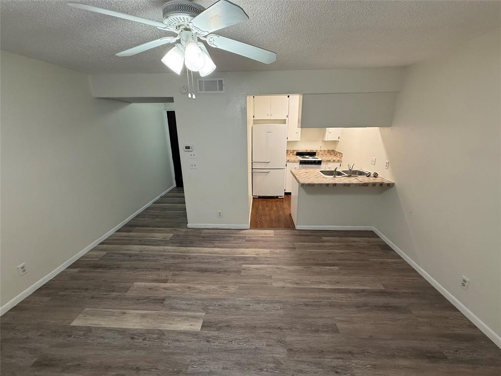 2408 Longview Street, Unit 104 Austin, TX 78705 - Photo 2 of 5 Kitchen featuring light countertops, a textured ceiling, white appliances, dark wood finished floors, and a peninsula