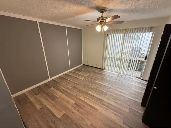 an empty room with wooden floor and fan