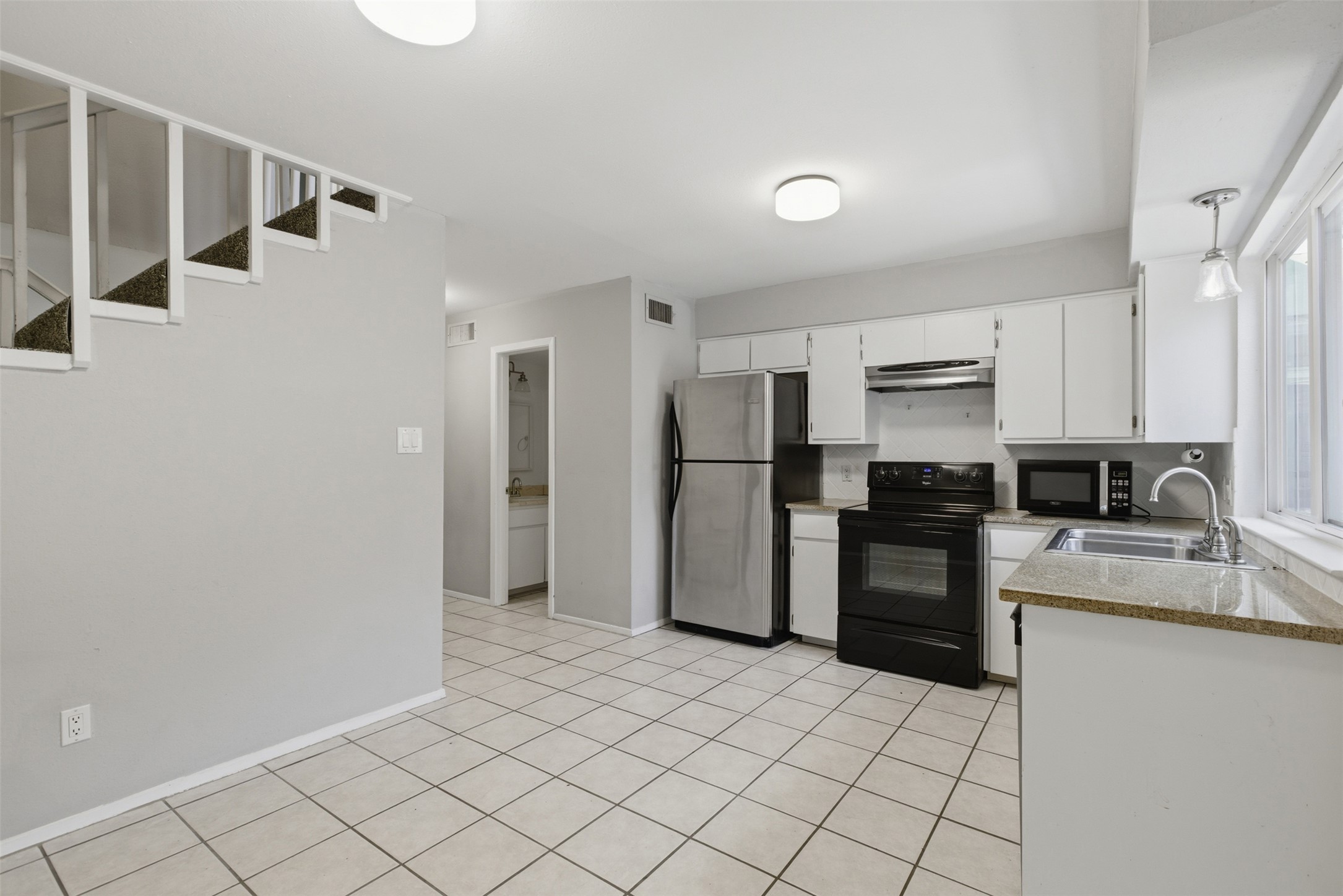 4204 Hudson Bend Road, Unit B Austin, TX 78734 - Photo 13 of 37 Open-concept kitchen featuring white cabinetry, black range, stainless steel refrigerator, and stone-finish countertops