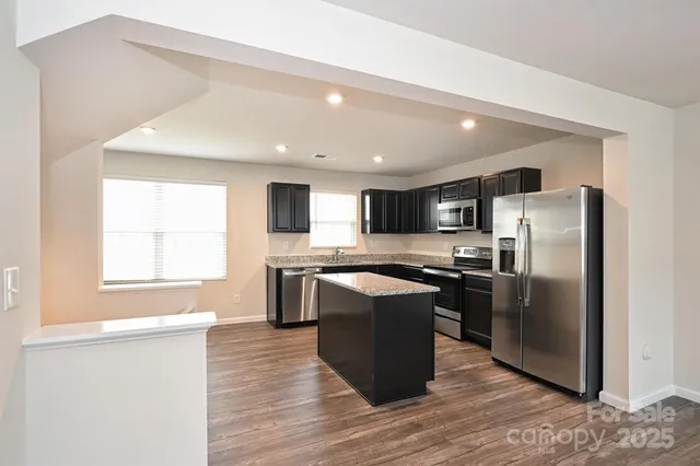 a kitchen with stainless steel appliances granite countertop a refrigerator a sink a stove and oven