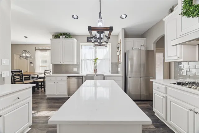 a kitchen with refrigerator a stove and white cabinets