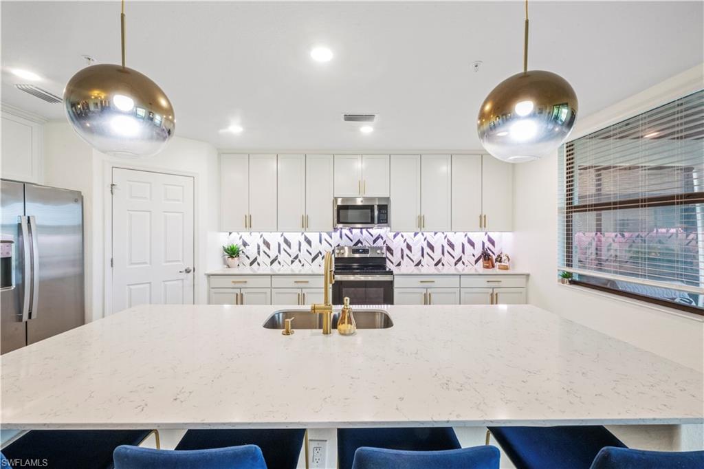2373 Anguilla Drive, Unit 101 Naples, FL 34120 - Photo 9 of 32 a kitchen with kitchen island granite countertop a table and chairs