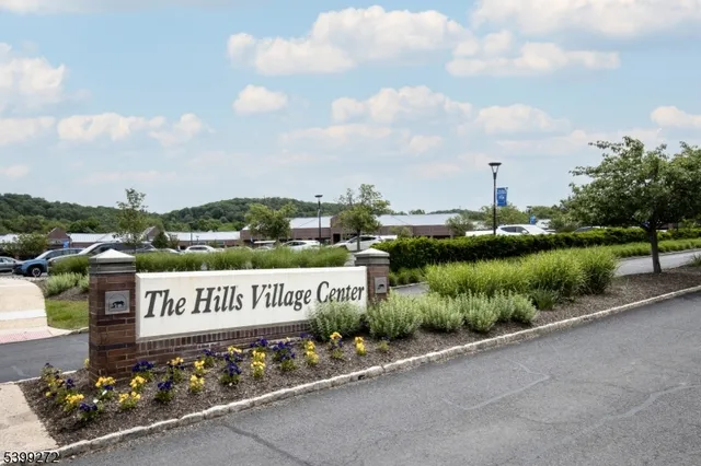 a view of a sign board with a garden and trees