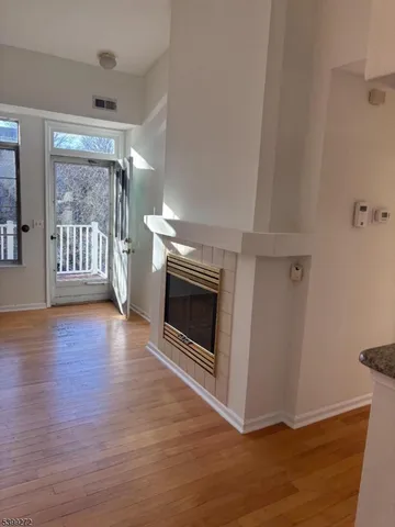 a view of a livingroom with wooden floor a fireplace and window