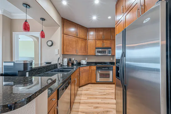 a kitchen with stainless steel appliances granite countertop a sink and a refrigerator