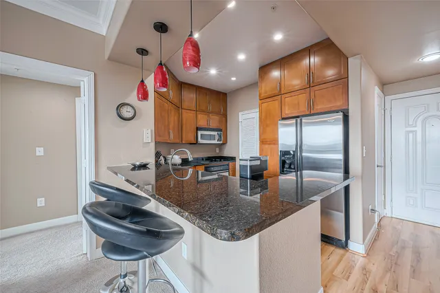 a kitchen with stainless steel appliances granite countertop a sink a refrigerator and a wooden cabinets