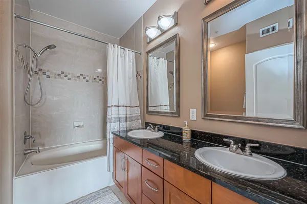 a bathroom with a granite countertop sink and a mirror a bathtub