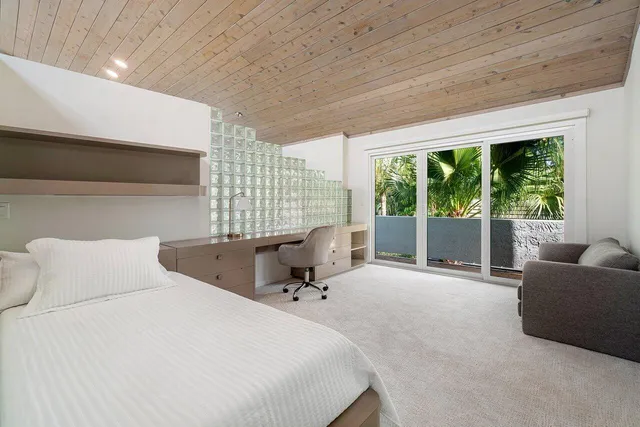 a bedroom with a bed and large windows