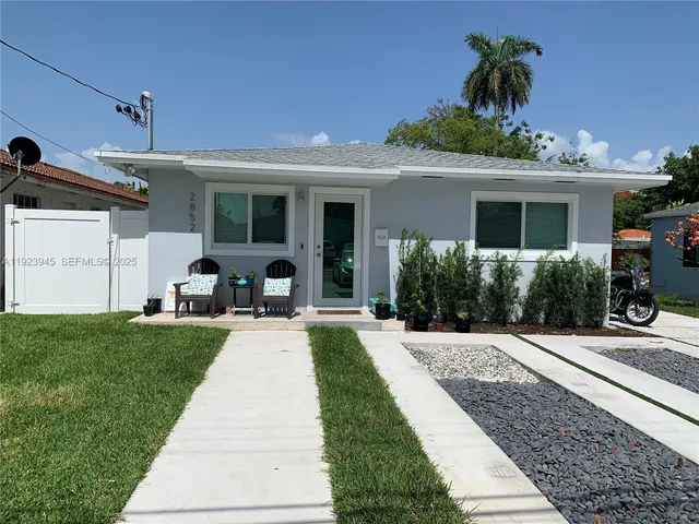 a front view of a house with a yard and potted plants