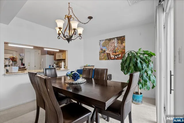 a dining room with wooden floor a chandelier a wooden table and chairs