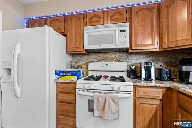 a kitchen with stainless steel appliances granite countertop a refrigerator sink stove and white cabinets