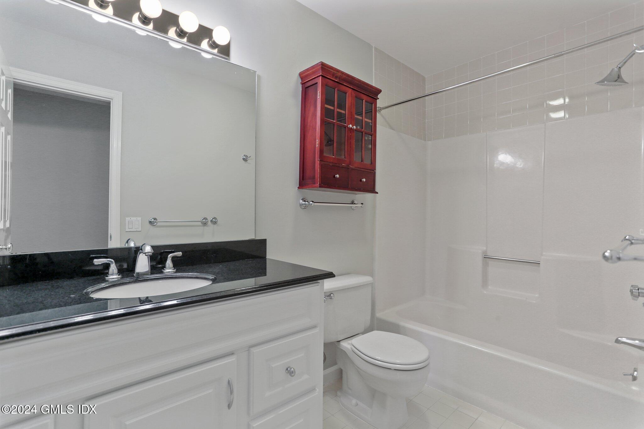 53 Bible Street, Unit 4 Cos Cob, CT 06807 - Photo 17 of 28 a bathroom with a granite countertop sink a toilet a mirror and shower