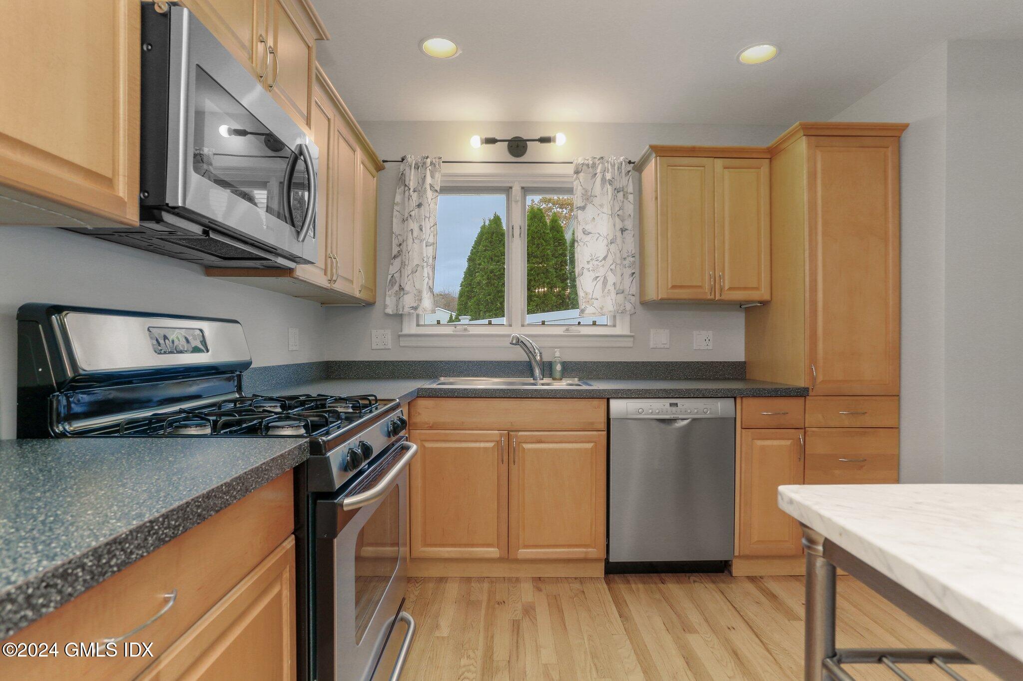 53 Bible Street, Unit 4 Cos Cob, CT 06807 - Photo 5 of 28 a kitchen with stainless steel appliances granite countertop wooden cabinets stove top oven and sink