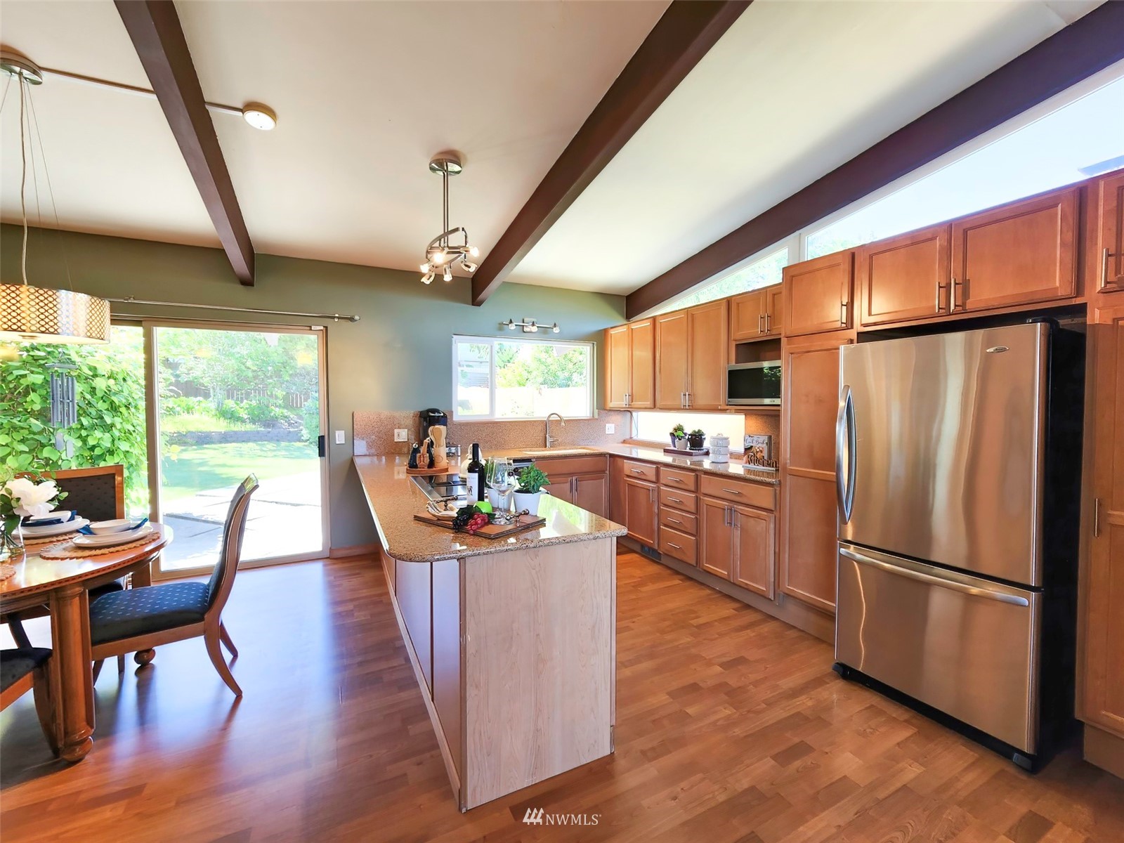 7133 South Sunnycrest Road Seattle, WA 98178 - Photo 16 of 39 a kitchen with stainless steel appliances a refrigerator a stove top oven a sink dishwasher and white cabinets with wooden floor