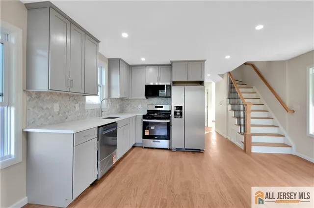 a kitchen with granite countertop a refrigerator and a stove top oven