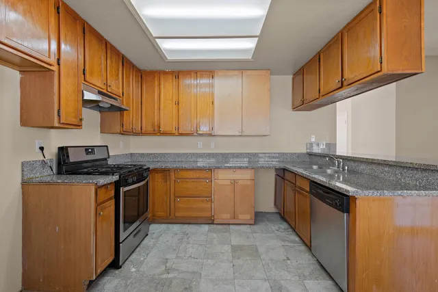 a kitchen with stainless steel appliances granite countertop a stove a sink and a microwave