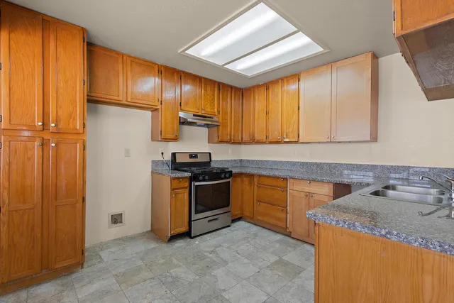 a kitchen with granite countertop a sink stainless steel appliances and cabinets