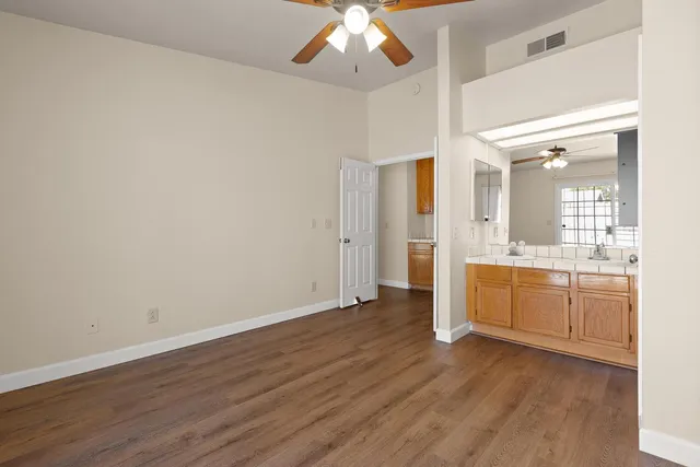 an empty room with wooden floor and a kitchen