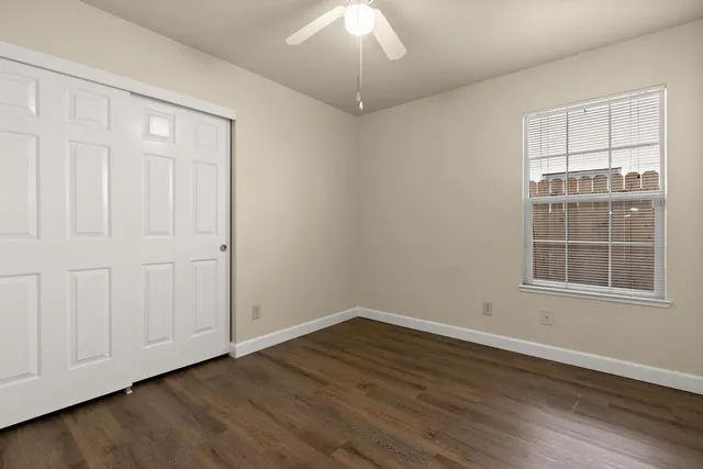 an empty room with wooden floor cabinet and windows
