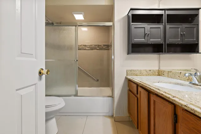 a bathroom with a granite countertop sink a toilet and shower
