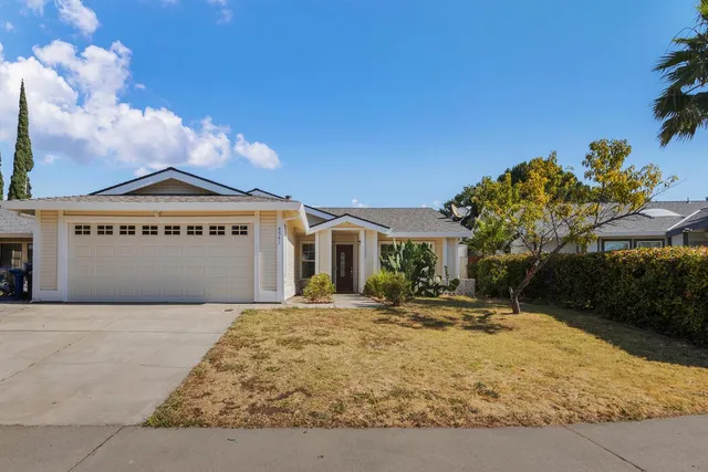 a front view of a house with a yard and potted plants