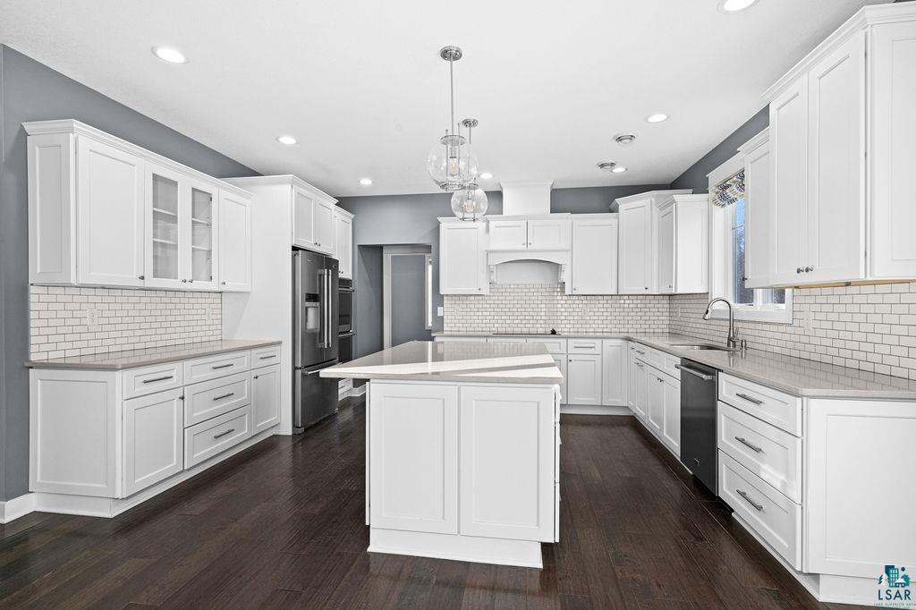 3879 Okerstrom Road Hermantown, MN 55811 - Photo 6 of 32 Kitchen with white cabinets, hanging light fixtures, dark wood finished floors, a center island, and stainless steel appliances