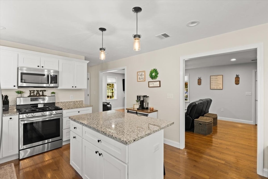 25 Upton Street Hanson, MA 02341 - Photo 8 of 30 a kitchen with kitchen island granite countertop a stove top oven a sink a counter space and cabinets