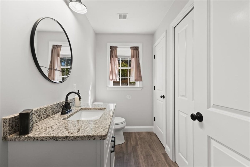 25 Upton Street Hanson, MA 02341 - Photo 10 of 30 a bathroom with a granite countertop toilet a sink and a mirror