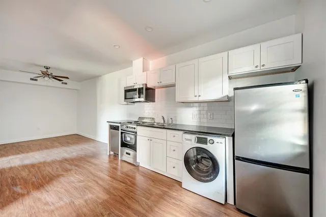a view of kitchen with stainless steel appliances granite countertop a refrigerator and a stove top oven