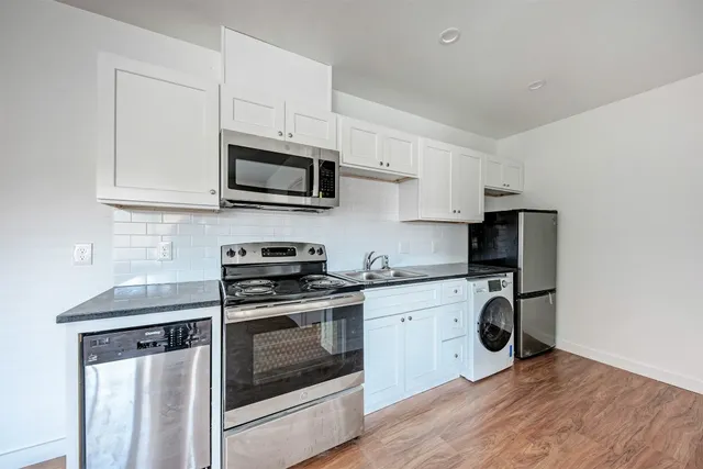 a kitchen with granite countertop wooden cabinets stainless steel appliances and a sink