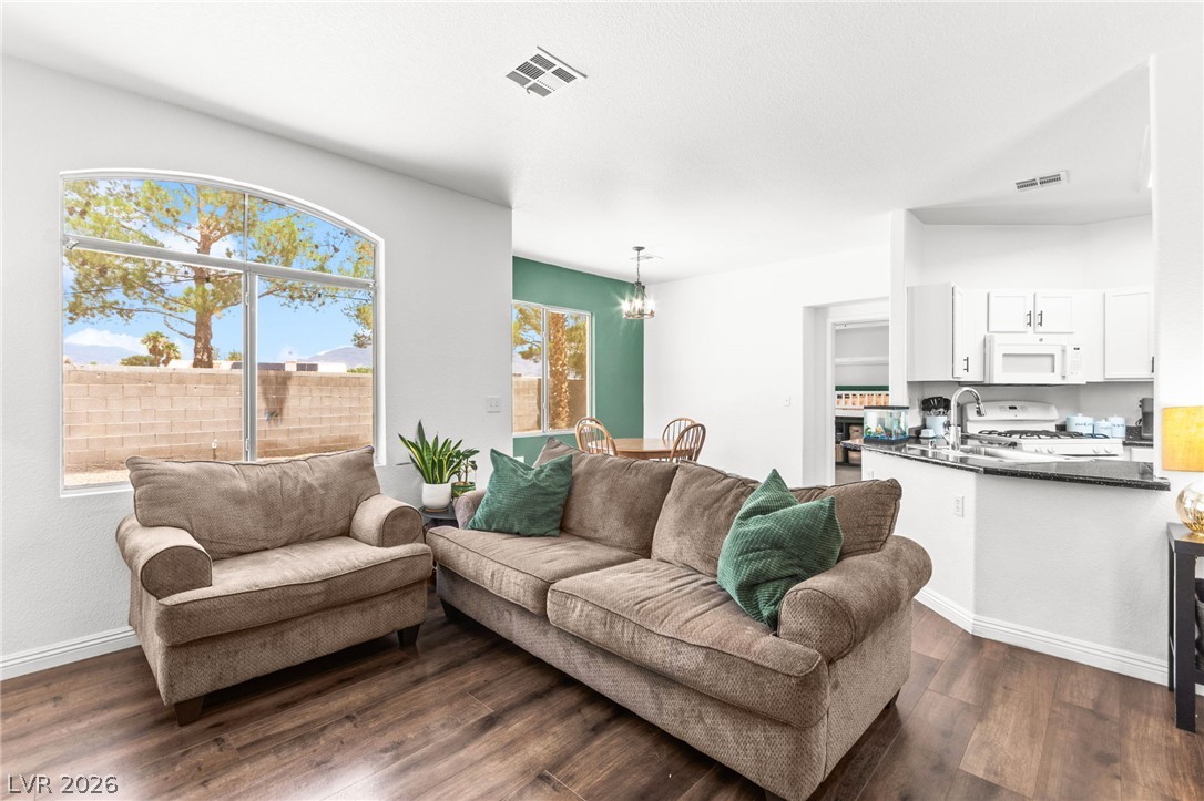 7353 Ridge Star Court Las Vegas, NV 89131 - Photo 12 of 36 Natural light floods this inviting space, featuring rich hardwood floors and a modern kitchen with a view.
