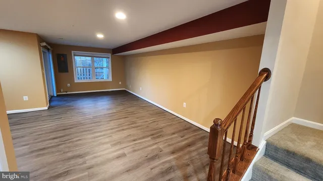 a view of an empty room with wooden floor and stairs