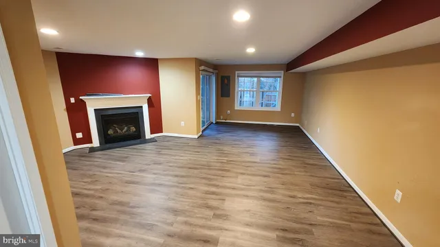 an empty room with wooden floor fireplace and windows