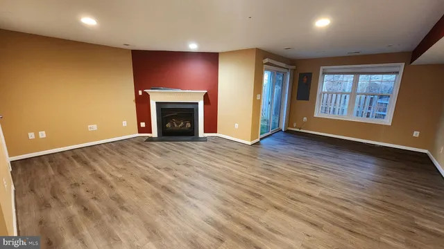 an empty room with windows fireplace and wooden floor