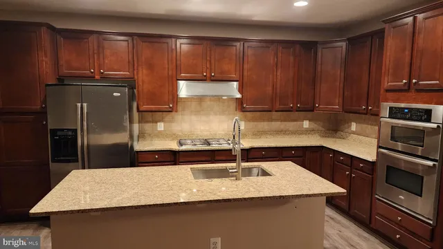 a kitchen with kitchen island granite countertop a sink a stove and refrigerator